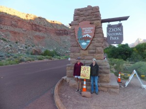 (L-R) Wendy Harris, a Springdale buisness owner, and Teresa Soper, who drives a park tour bus, stand outside of the entrance of Zion National Park asking whoever will pay attention to help "save out parks," Springdale, Utah, Oct. 1, 2013 | photo by Dan Mabbutt, St. George News