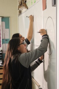 Casey Velarde, key wardrobe for the production, and Kelcy Faimalo, makeup and hair, draw some shapes on a whiteboard for the production of "Triangle Power" in Cedar City High School on Oct. 14, 2014 | Photo by Devan Chavez, St. George News  