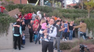 Jared Keddington, Heart of Dixie promoter, carrying his daughter while protesters dance behind him, St. George, Utah, Nov. 6, 2014 | Photo by Mori Kessler, St. George News