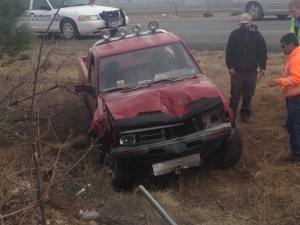 A red Nissan pickup truck sits along Interstate 15 after it ran through the fence and rolled, St. George, Utah, Dec. 31, 2014 | Photo by Holly Coombs, St. George News