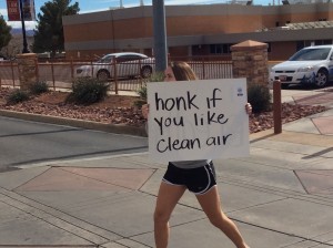 Tori Woodman displays a sign as she crosses the 900 East crosswalk on 100 South at the Clean Air No Excuses rally, St. George, Utah, Jan. 31, 2015 | Photo by Holly Coombs, St. George News