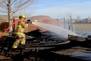 A Washington A Washington City Firefighter sprays water on the remains of a shed that caught fire Monday afternoon after wind reignited the remains of an agricultural burn, Washington City, Utah, Feb. 16, 2014 | Photo by Devan Chavez, St. George News 