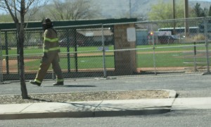 A firefighter in full gear heads toward a beehive at Elks Field Friday | Photo by Ric Wayman, St. George News