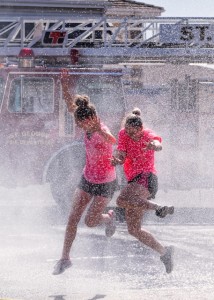 Racers run through the spray of a fire truck hose, location and date not specified | Photo by Dave Becker courtesy of Fire Hose Frenzy, St. George News