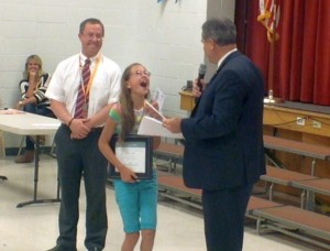 L-R Sunset Elementary principal Anthony Horrocks looks on as student Annabel Smith receives a $100 check and certificate from Mayor Jon Pike Friday May 1, 2015 | Photo by Ric Wayman, St. George News