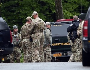 Law enforcement officers gather on a road on Sunday, June 28, 2015, in Malone, N.Y. The shooting death of one escaped killer brought new energy to the three-week hunt for a second escaped murderer in the United States as helicopters, search dogs and hundreds of law enforcement officers converged on a wooded area 30 miles from Clinton Correctional Facility| Photo by  AP Mike Groll, St. George News