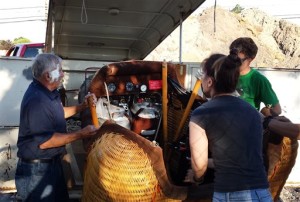 In this photo provided by Kevin Auernig, the pilot of a hot air balloon, which crash landed, helps put his basket back in his trailer after he was treated by paramedics for cuts to his face, in Provo, Utah on Thursday, July 2, 2015. The Bank of American Fork piggy bank hot air balloon crashed into a tree and caught fire at a balloon festival in Utah. (Kevin Auernig via AP)