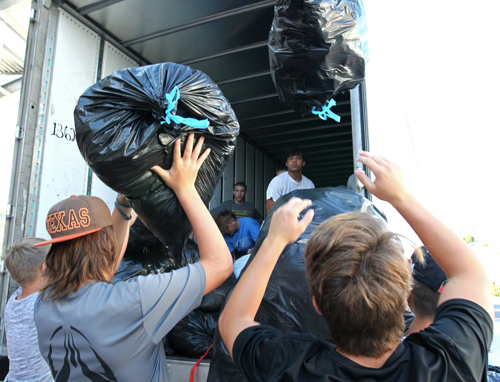 Players from the Desert Hills Football team load bags of donated clothes into a semi-truck to be taken to the I Won't Cheat Foundation, Desert Hills Football Charity Fundraiser, St. George, Utah, Aug. 15, 2015, | Photo by Robert Hoppie, ASPpix.com, St. George News