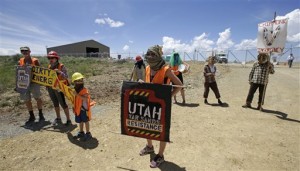 Protesters gather outside the U.S. Oil Sands commercial tar sands operation, in the Book Cliffs, in eastern Utah. On a remote Utah ridge covered in sagebrush, pines and wild grasses, a Canadian company is about to embark on something never before done commercially in the United States: digging sticky, black, tar-soaked sand from the ground and extracting the petroleum, Black Cliffs, Utah, July 13, 2015 | AP Photo by Rick Bowmer, St. George News