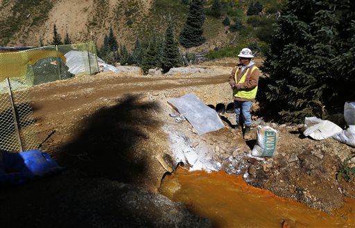 An Environmental Protection Agency contractor keeps a bag of lime on hand to correct the PH of mine wastewater flowing into a series of sediment retention ponds, part of danger mitigation in the aftermath of the blowout at the site of the Gold King Mine, outside Silverton, Colo. Federal officials say they have suspended cleanup work and investigations covering 10 mining sites in four states to guard against a repeat of last months massive wastewater spill from an inactive Colorado gold mine. Details provided to The Associated Press show the order applies to three sites in California, four in Colorado, two in Montana and one in Missouri. Outside Silverton, Colo., Aug. 14, 2015 | AP File Photo by Brennan Linsley, St. George News