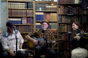 In this May 23, 2015, photo, Duncan Phillips, center, performs a song by songwriter Joe Hill along with Morgan Snow, left, and Kate MacLeod at Ken Sanders Rare Books in Salt Lake City. The event raised funds for a Joe Hill memorial concert planned for September in Sugar House Park. Hill was executed in Utah on Nov. 19, 1915, after being convicted of a murder many people believe he did not commit, Salt Lake City, Utah, May 23, 2015 | AP Photo by Jeremy Harmon, The Salt Lake Tribune, JOWHILL.SLTRIB.COM, St. George News 