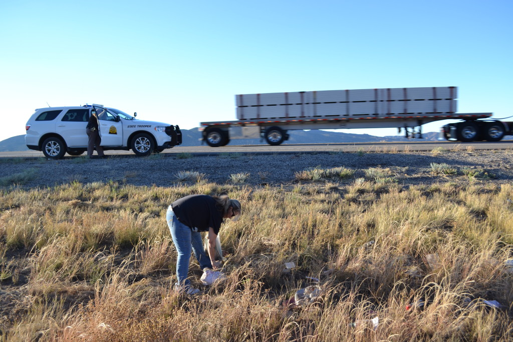 Tobi Kerby picks up a woman's scattered belongings after the woman rolled off I-15, Parowan, Utah, Oct. 11, 2015 | Photo by Emily Hammer, St. George News