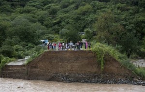 People stand at the edge of a collapsed bridge, overlooking the Ameca River in Cofradia, some 200 km northwest of Guadalajara, Mexico. Hurricane Patricia made landfall Friday on a sparsely populated stretch of Mexico's Pacific coast as a Category 5 storm, avoiding direct hits on the resort city of Puerto Vallarta and major port city of Manzanillo as it weakened to tropical storm force while dumping torrential rains that authorities warned could cause deadly floods and mudslides, Guadalajara, Mexico, Saturday, Oct. 24, 2015 | AP Photo/Eduardo Verdugo, St. George News