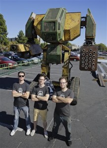 MegaBots founders from left, Brinkley Warren, Matt Oehrlein and Gui Cavalcanti stand below their 15-foot tall, piloted Mk.II robot at the Pioneer Summit in Redwood City, Calif. Let the giant robot wars begin. A team of American engineers challenged a group in Japan to a battle for robot supremacy, and the Japanese said bring it on. So Oakland-based MegaBots has launched a Kickstarter campaign to raise money to turn the Mk.II, into a real fighting machine, ready for hand-to-hand combat, Oct. 9, 2015 | AP Photo by Eric Risberg, St. George News