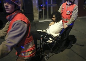 A woman is being evacuated from the Bataclan theater after a shooting in Paris, Friday Nov. 13, 2015. French President Francois Hollande declared a state of emergency and announced that he was closing the country's borders. (AP Photo/Thibault Camus)