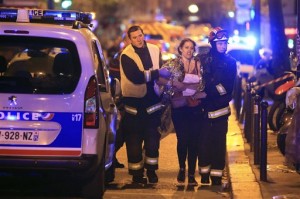 Rescue workers help a woman after a shooting, outside the Bataclan theater in Paris, Friday Nov. 13, 2015. French President Francois Hollande declared a state of emergency and announced that he was closing the country's borders. (AP Photo/Thibault Camus)