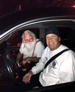 Lone Peak Fire District Battalion Chief Joseph McRae, right gives a ride to Orem, Utah resident Steven Macey, a Santa-for-hire, a ride to a home to deliver presents after fire crews put out a fire in Maceys car. Firefighters called to the car fire in the Utah suburb got a big surprise early Christmas morning when they discovered the stranded driver turned out to be Santa Claus on the way to deliver presents. Alpine, Utah, Dec. 25, 2015 | Photo by Lt. Dustin Mitchell/Lone Peak Fire District via AP, St. George News