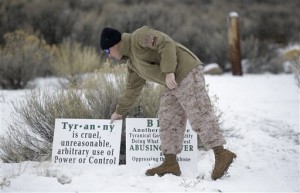 Jon Ritzheimer, of Arizona, a member of the group occupying the Malheur National Wildlife Refuge headquarters, adjust a sign. Law enforcement had yet to take any action Tuesday against the group numbering close to two dozen who are upset over federal land policy. Tuesday, Jan. 5, 2016, near Burns, Oregon, Jan. 5, 2015 | AP Photo/Rick Bowmer, St. George News