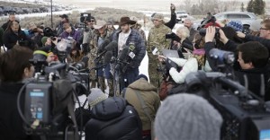 Ammon Bundy, center, one of the sons of Nevada rancher Cliven Bundy, speaks with reporters during a news conference at Malheur National Wildlife Refuge headquarters Monday, Jan. 4, 2016, near Burns, Ore. Bundy, who was involved in a 2014 standoff with the government over grazing rights, told reporters on Monday that two local ranchers who face long prison sentences for setting fire to land have been treated unfairly. The armed anti-government group took over the remote national wildlife refuge in Oregon as part of a decades-long fight over public lands in the West, Malheur National Wildlife Refuge, Oregon, Jan. 4, 2016 | AP Photo/Rick Bowmer, St. Goerge News