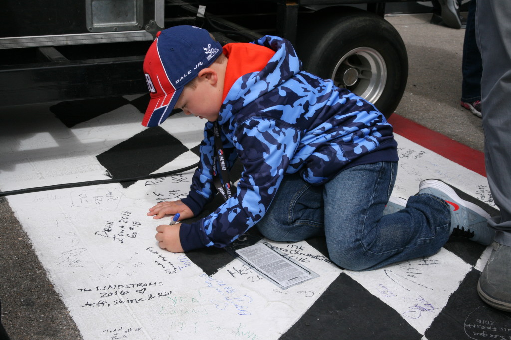 A young NASCAR fan puts his mark on the start/finish line at the Kobolt 400, Las Vegas, Nev., Mar. 6, 2016. | Photo by Rick Johnson, special to St. George News 