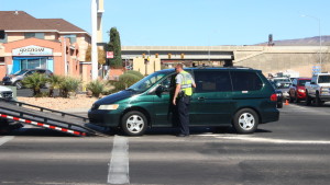 A Washington City police officer looks on as a Honda minivan is loaded onto a tow truck after a collision at the intersection of Green Springs Drive and Telegraph Street 1in Washington City, Utah, Mar. 19, 2016 | Photo by Don Gilman, St. George News