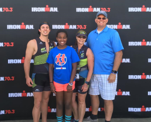 L-R Colton Gust, Alexis Gust, Tiffany Gust and Dave Gust pose for a photo in front of an Ironman 70.3 logo. Location and date not specified | Photo courtesy of Tiffany Gust, St. George News