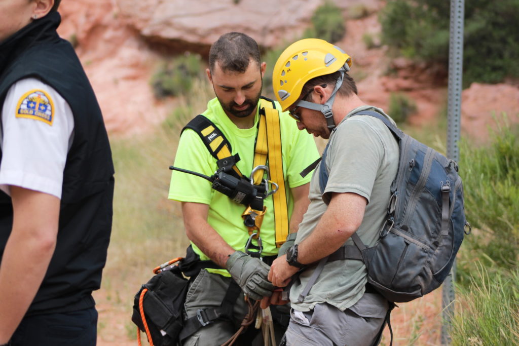 Iron County Sheriff's Ropes Team member helps rescued hiker remove his safety harness after he was rescued from 600-foot cliff in Cedar City Saturday, Cedar City, Utah, June 11, 2016 | Photo by Tracie Sullivan, St. George/Cedar City News