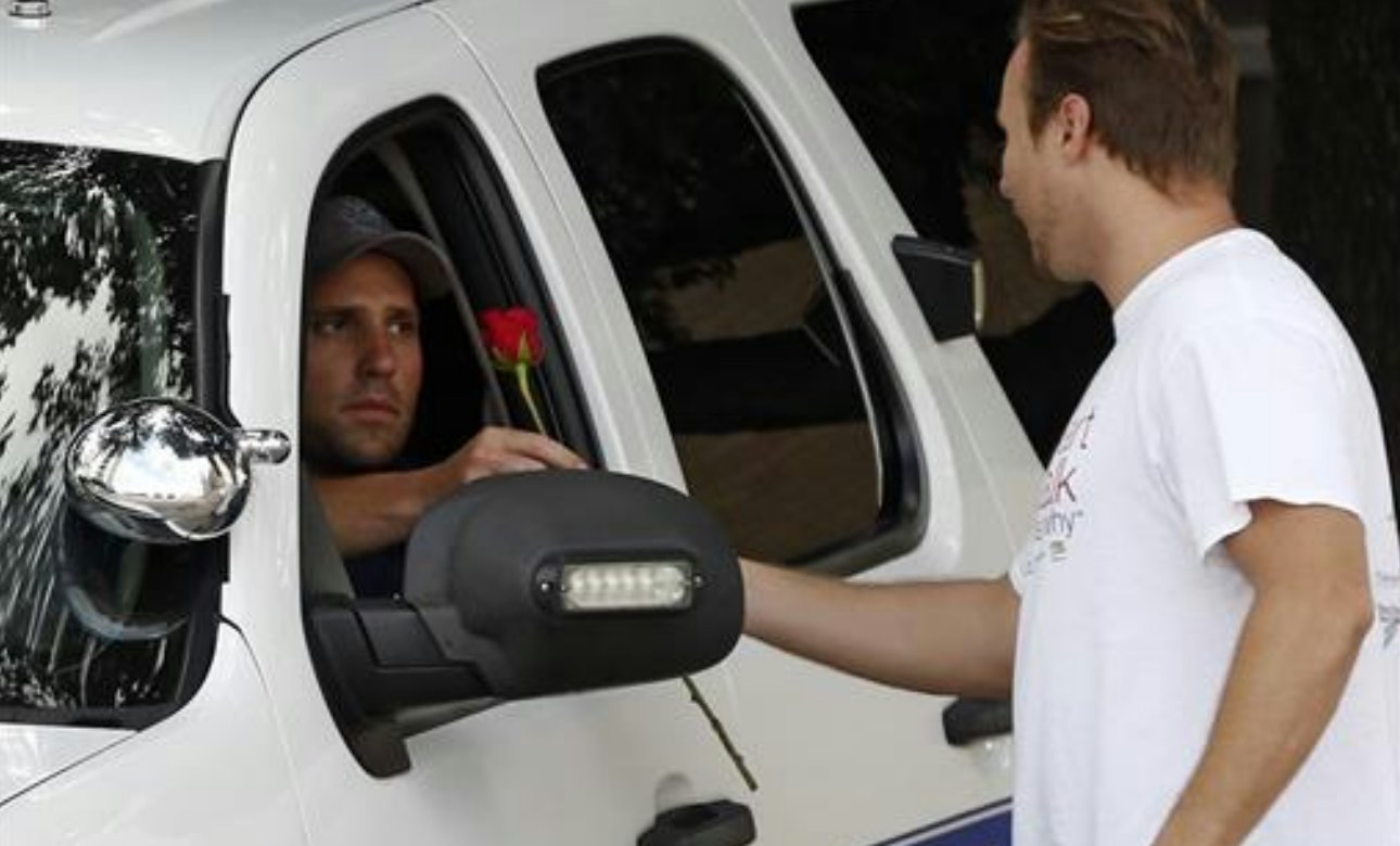 John Fife hands a police officer guarding Jack Evans Police Headquarters a rose in Dallas. Snipers opened fire on police officers in the heart of Dallas during protests over two recent fatal police shootings of black men, Dallas, Texas, Friday, July 8, 2016 | Photo courtesy of Nathan Hunsinger/The Dallas Morning News via The Associated Press, St. George News