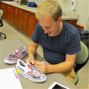 Jacob Amundsen decorates shoes at 2013 Day of the Walking Dead, Location not given | Photo courtesy of Southern Utah University, St. George News, Cedar City News