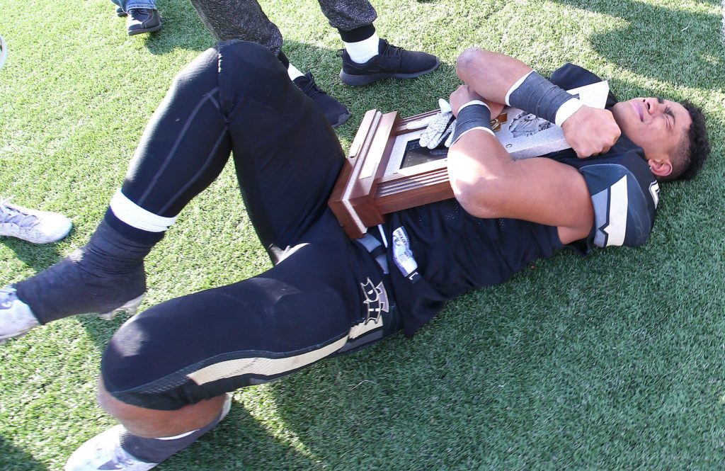 Desert Hills' Nephi Sewell (2) is overcome with emotion as he hugs the championship trophy, Desert Hills vs. Pine View, 3AA State Championship, Football, Salt Lake City, Utah, Nov. 18, 2016, | Photo by Robert Hoppie, ASPpix.com, St. George News