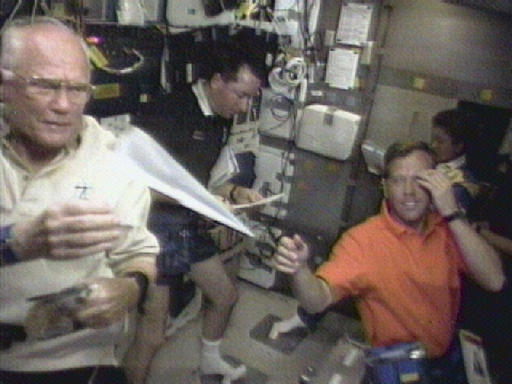 FILE - In this Sunday, Nov. 1, 1998 image made from video, astronaut John Glenn, left, retrieves a paper airplane for pilot Steven Lindsey, foreground right, in the space shuttle Discovery's middeck. Astronaut Stephen Robinson, background right, and Japanese astronaut Chiaki Mukai look over paper work in the background. Glenn died Thursday, Dec. 8, 2016, at the age of 95. (AP Photo/NASA, File)