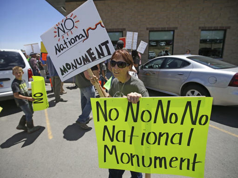 File Photo: In this file photo, a protester holds her signs after U.S. Interior Secretary Sally Jewell arrived for a meeting with San Juan County Commissioners in Monticello, Utah. President Barack Obama designated two national monuments Wednesday, Dec. 28, at sites in Utah and Nevada that have become key flashpoints over use of public land in the U.S. West. The White House says Bears Ears National Monument in Utah will cover 1.35 million acres of tribal land in the Four Corners region. Monticello, Utah, July 14, 2016 | AP Photo/Rick Bowmer, File, St. George News