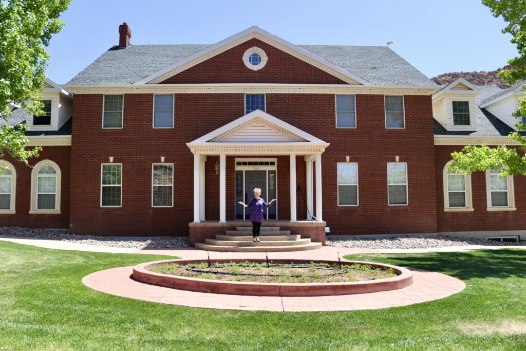 Leanne Worwood stands in front of Rockmore Retreats, a home she and her husband purchased and renovated, Hildale, Utah, May 2, 2022 | Photo by Jessi Bang, St. George News