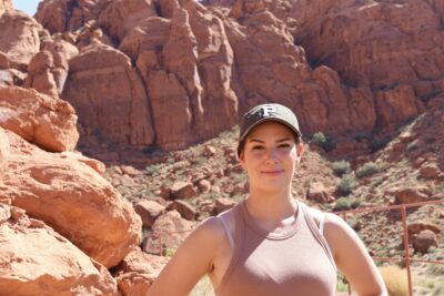 Artist Ashlie Davenport smiles for a photo against the red rocks of Tuacahn Amphitheatre, Ivins, Utah, May 17, 2022 | Photo by Jessi Bang, St. George News