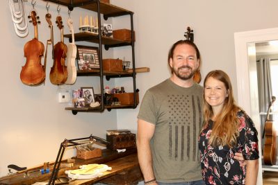 Chris and Jackie Hobson pose together inside their violin shop, St. George, Utah, July 11, 2022 | Photo by Jessi Bang, St. George News