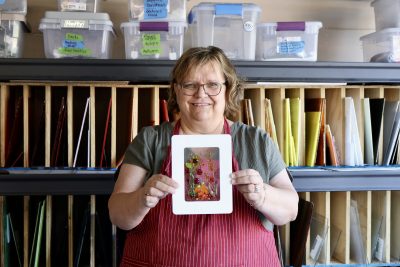 Nan Johnson stands inside her garage studio holding one of her art pieces, Washington, Utah, Oct. 5, 2022 | Photo by Jessi Bang, St. George News