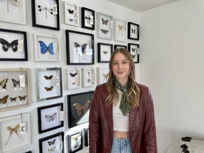 Ashlin Gubler, owner of Butterfly Effect Studio, stands next to a wall of her work, St. George, Utah, Jan. 23, 2023 | Photo by Jessi Bang, St. George News