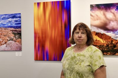 Photographer and creator Shirley Smith stands next to her solo show display at The Tilted Kiln Gallery in St. George, Utah, Sept. 27, 2023 | Photo by Jessi Bang, St. George News