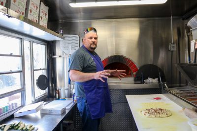 Blazin Hearth Mobile Wood Fired Kitchen owner Kendall Pipkin prepares a signature pizza inside his trailer at Sunbrook Golf Course, St. George, Utah, April 9, 2024 | photo by Jessi Bang, St. George News